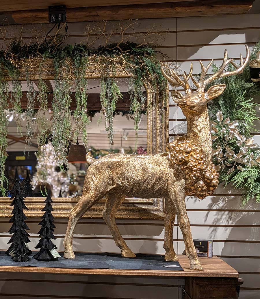Winter home decor featuring a large golden deer with wreath around its neck