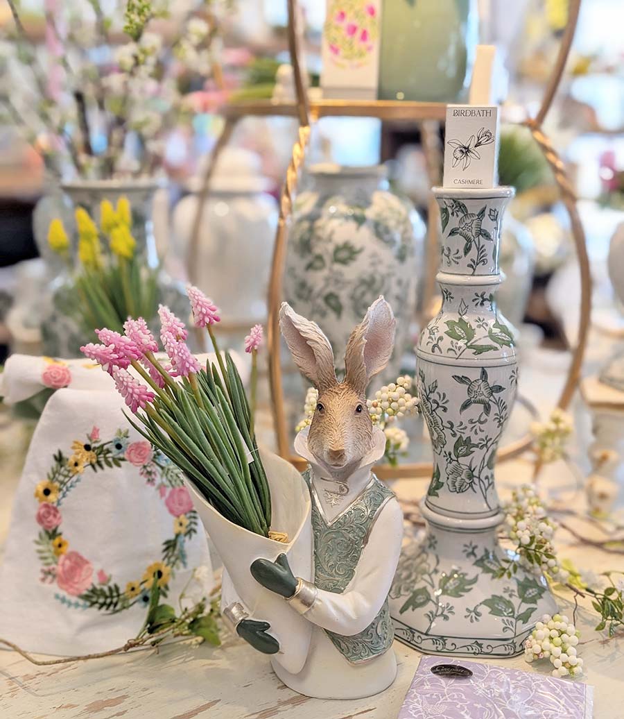 Spring home decor featuring a rabbit bust holding faux flowers, cloth napkins with a floral pattern, and a white vase with green floral pattern